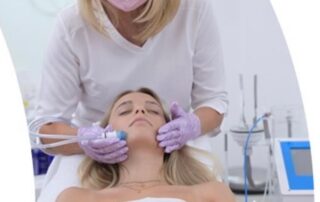 Junge Frau auf Behandlungsliege während Ästhetik-Gesichtsbehandlung. Dahinter Therapeutin mit Mund- und Handschutz